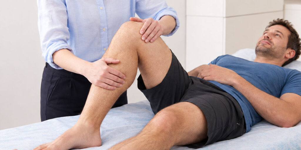 Osteopathin behandelt Knie eines Sportlers in Rückenlage